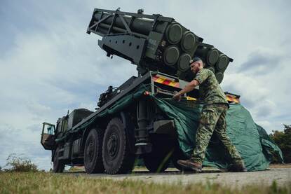 Een militair bevestigt een gronddoek rondom een raketlanceerinstallatie.