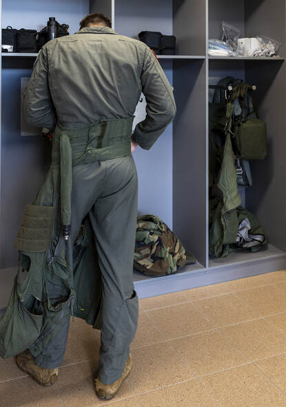 Een F-16 vlieger trekt zijn vliegeroverall aan.