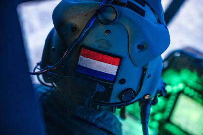 De helm van een apachevlieger, met op de achterkant een Nederlandse vlag. Daarnaast de simulator van de Apache Echo, waarbij de cockpit in een u-vorm van beeldschermen is geplaatst.