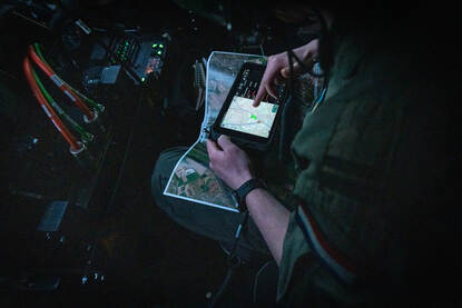 Een vlieger met op zijn schoot een landkaart en een klein beeldscherm.