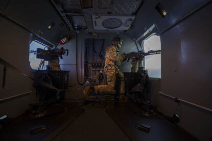 Een doorgunner in de simulator. Met één knie leunt hij op een verhoging, zijn andere voet staat op de grond. Met zijn handen houdt hij het wapen vast.