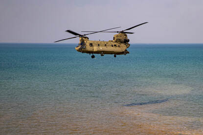 Links: Een Chinook vliegt boven een rivier. Rechts: Een Chinook vliegt boven een groot meer.