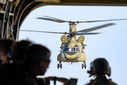 Links: Een vliegende Chinook gezien vanuit de achterkant van een andere Chinook. Rechts: Een Chinook draait in de lucht scherp weg van de fotograaf.