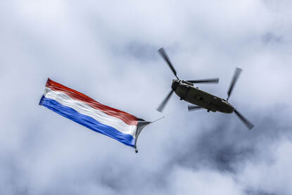 Een gigantische Nederlandse vlag hangt onder een Chinook.