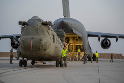 Transporthelikopter wordt in ruim vliegtuig geschoven.