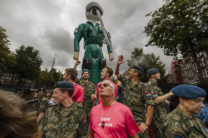 Militairen en burgers op de defensieboot met achter hen een opblaasbare luchtmachtmilitair.