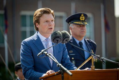 Links: Defensieminister Ruben Brekelmans speecht tijdens de uitreiking. Rechts: Adjudant Raijmann luistert naar de speech.