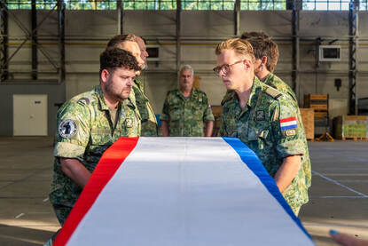 De ploeg loopt strak in de pas richting de kist. Daarna tillen ze deze op de schouders.