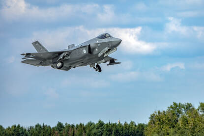 Een F-35 stijgt op en klapt net zijn wielen in.
