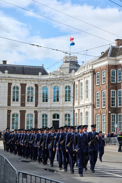 Een marcherende groep luchtmachters met wapens in de hand.