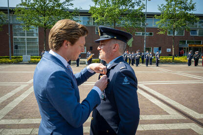 Minister Brekelmans speldt het Vliegerkruis op bij reservekapitein Michiel (links) en CDS Eichelsheim feliciteert hem daarna (rechts).