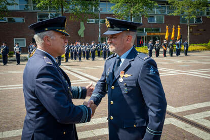 Minister Brekelmans speldt het Vliegerkruis op bij reservekapitein Michiel (links) en CDS Eichelsheim feliciteert hem daarna (rechts).