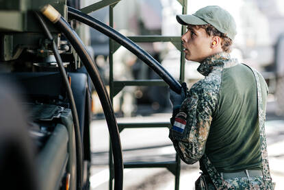 Een militair volgt heel precies hoe een kabel in een voertuig gaat.