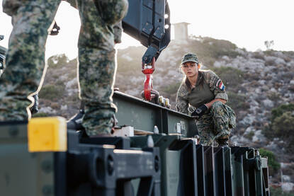 Een vrouwelijk militair is bezig met het in de juiste positie brengen van een hijs-oog.