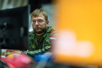 Foto van een militair die geconcentreerd naar zijn computer kijkt.