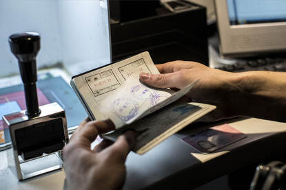 Met een hand wordt door een paspoort gebladerd.