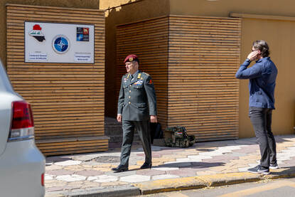 Generaal Cas Schreurs loopt naar een voertuig. Daarnaast praat een onherkenbare BSB’er in een oortje.