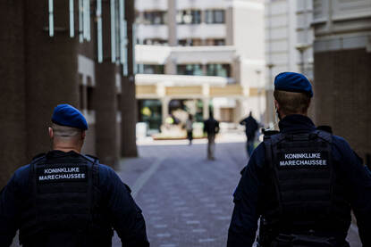 2 beveiligers van de marechaussee lopen gezamenlijk door een smalle straat.