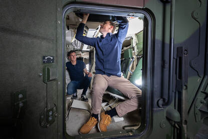 Stagiair Etiën Tax en begeleider Erik van Uem bekijken het interieur van een Boxer pantservoertuig.