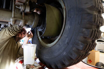 Monteur met kwast in een wielkast van een voertuig.